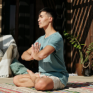 Persona realizando estiramientos o pose de yoga en la naturaleza.